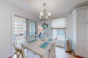 uma sala de jantar branca com uma mesa e cadeiras brancas em Aronimink Vista 9C em Ocean City