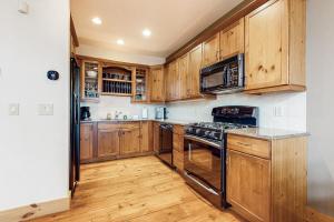 cocina con armarios de madera y horno con fogones en Vermont Mountain Chalet, en Stratton