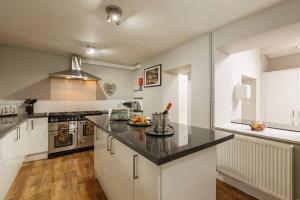 a kitchen with white cabinets and a black counter top at NEW The Green House Cromer Sleeps 20 Hot Tub in Thorpe Market