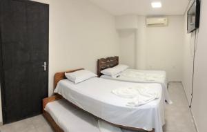Duas camas num quarto com lençóis e almofadas brancos em Hotel Cuiabá em Cuiabá