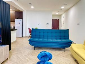a blue couch in a living room with a kitchen at Lovely Private Contemporary Residential Apartment - 201 in Abu Dhabi