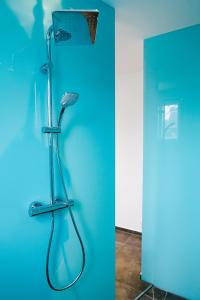 une douche dans un mur bleu avec un pommeau de douche dans l'établissement Louis & Louise Penthouse I Digital Check In, à Brême