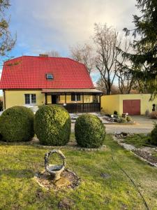 uma casa com um telhado vermelho e alguns arbustos em Zaczarowany Bieślin em Trzemeszno