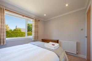 1 dormitorio con cama y ventana grande en Cuilreigh, North Connel, en Oban