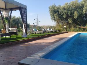 a swimming pool with chairs and a gazebo next to a resort at Giardino di Circe in Agrigento