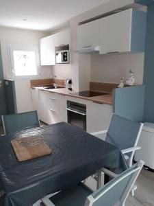 a kitchen with a table and chairs and a table and a kitchen with white at Les cottages du golf à Ploemel in Ploemel