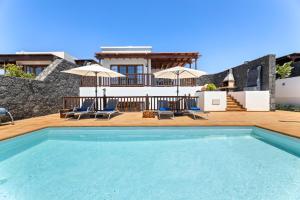 une piscine avec des chaises et des parasols ainsi qu'une maison dans l'établissement Lanzarote Villa Ascanio, à Playa Blanca