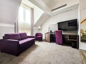 a living room with a purple couch and a tv at Valemi Stay - Selfservice in Düsseldorf