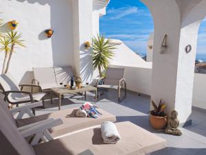 Un patio con sillas y mesas en un balcón. en Beautiful apartment with amazing Sea view, en Nerja
