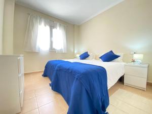 1 dormitorio con cama con sábanas azules y ventana en Soleada PBaja con Gran Terraza a pie de piscina Altaona Golf en Murcia