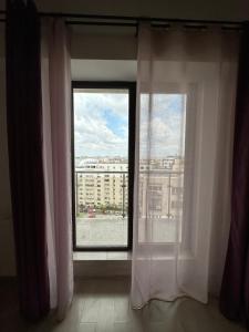 - une fenêtre avec des rideaux blancs et une vue sur un bâtiment dans l'établissement 97 RENT House, à Bucarest