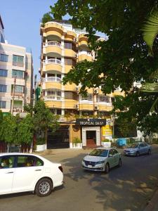 Zwei Autos parkten auf einem Parkplatz vor einem Gebäude. in der Unterkunft Tropical Daisy - Lake View in Dhaka