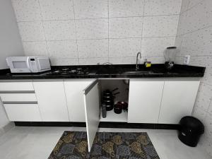 uma cozinha com um lavatório e um micro-ondas em Aquarela Apart Hotel em Sinop