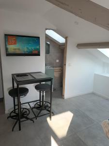 una camera con tavolo, due sgabelli e una TV a parete di Studio Anthėor, vue mer a Saint-Raphaël