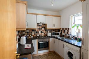 a kitchen with white cabinets and black counter tops at New Street Corner in Dungiven