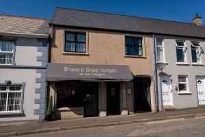 a building with a sign that reads shine n shed gardeners at New Street Corner in Dungiven