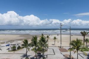 uma praia arenosa com palmeiras e o oceano em Apto Jóia 3 dormitórios - Frente para o mar - Praia Grande na Praia Grande
