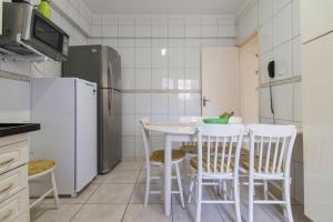uma cozinha com uma mesa e cadeiras e um frigorífico em Apto Jóia 3 dormitórios - Frente para o mar - Praia Grande na Praia Grande