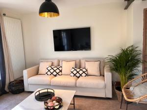 uma sala de estar com um sofá e uma televisão na parede em Honfleur - grande maison familiale avec jardin em Honfleur