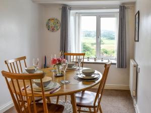 a dining room with a table with chairs and a window at Hyfrydle Cottage in Pen-y-groes