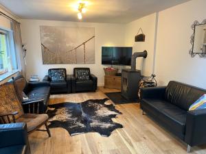a living room with black leather couches and a tv at Rivendell I3 in Monschau