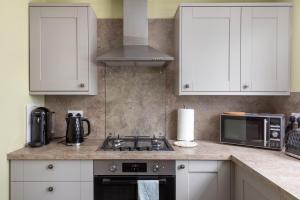 a kitchen with white cabinets and a stove and microwave at The Edinburgh Rooftop Terrace in Edinburgh