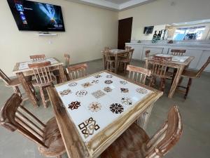 Pousada Donna Maraka في بورتو دي غالينهاس: غرفة طعام مع طاولة وكراسي وتلفزيون
