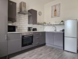 eine Küche mit grauen Schränken und einem Kühlschrank in der Unterkunft DYSA Abbey House in Blackpool