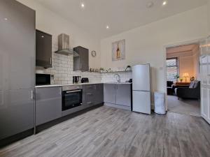 eine Küche mit Küchengeräten aus Edelstahl und ein Wohnzimmer in der Unterkunft DYSA Abbey House in Blackpool