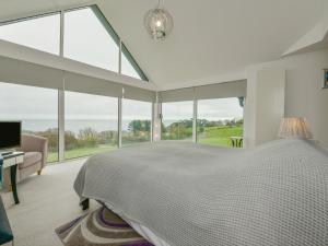 a white bedroom with a large bed and large windows at Skerries in Dartmouth