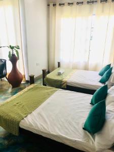 2 camas con almohadas verdes en una habitación en Barefoot Inn Kandy en Kandy