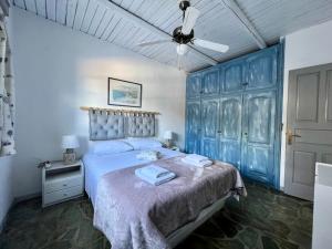 a bedroom with a blue bed with a ceiling fan at The Traditional Stone Villa in Koundouros