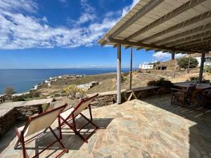 eine Terrasse mit 2 Stühlen, einem Tisch und Meerblick in der Unterkunft The Traditional Stone Villa in Koundouros