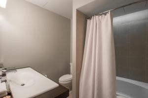 ein Badezimmer mit einem weißen Duschvorhang und einem WC in der Unterkunft Magnolia Hotel Denver, a Tribute Portfolio Hotel in Denver