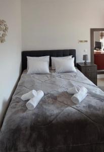 Una cama con dos pares de zapatillas blancas. en Bouvegio Apartments Giorgos en Afántou