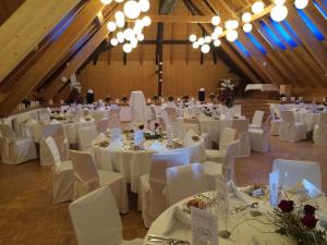 un salón de banquetes con mesas y sillas blancas y lámparas de araña en Restaurant Hotel Rüttihubelbad, en Walkringen