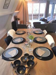 a wooden table with plates and wine glasses on it at Chalet Het Bosnestje Durbuy in Durbuy +35 photos