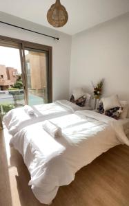 duże białe łóżko w pokoju z oknem w obiekcie Super appartement familial avec piscine à Prestigia Marrakech w Marakeszu