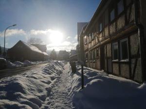 a snow covered street next to a building with the sun in the background at Günstige, schöne Ferienwohnung im Wanderparadies in Wernigerode
