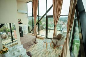 ein Wohnzimmer mit einem Sofa, einem Stuhl und Fenstern in der Unterkunft Hotel Grand View in Tbilisi in Tbilisi City