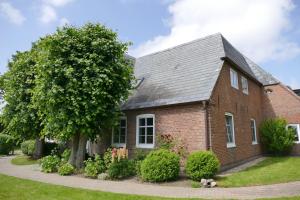 une maison en briques avec un arbre dans la cour dans l'établissement EBB und FLÖR, à Morsum