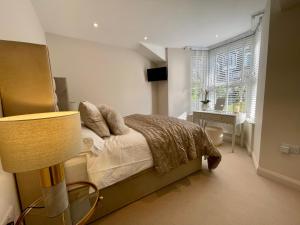 1 dormitorio con cama, lámpara y ventana en Heather Mere Cottage, Bowness-on-Windermere en Bowness-on-Windermere
