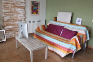 a bed with a blanket and a table with a laptop at Castell de Ceuró. Hotel Rural in Ogern