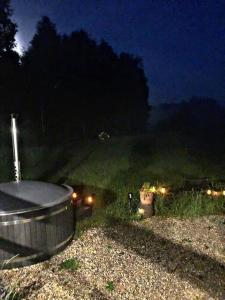 a hot tub in a field at night with lights at Oaza spokoju w lesie in Stara Kiszewa