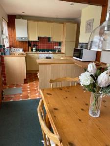 a kitchen with a wooden table with a vase of flowers at 32 Maescurig in Newport Pembrokeshire