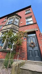 a brick house with a blue door and a tree at Riversdale House Bed & Breakfast in Llangollen