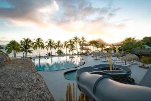a resort with a swimming pool and palm trees at Appartement terrasse vue mer et piscine in Le Diamant
