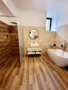 a bathroom with a tub and a sink and a mirror at SbOldTown Apartament in Braşov