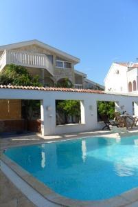 una grande piscina blu di fronte a una casa di Apartments Kafadar a Trogir