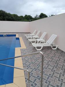 a row of white lounge chairs next to a swimming pool at 3A'S COASTAL GUEST HOUSE in Riambel